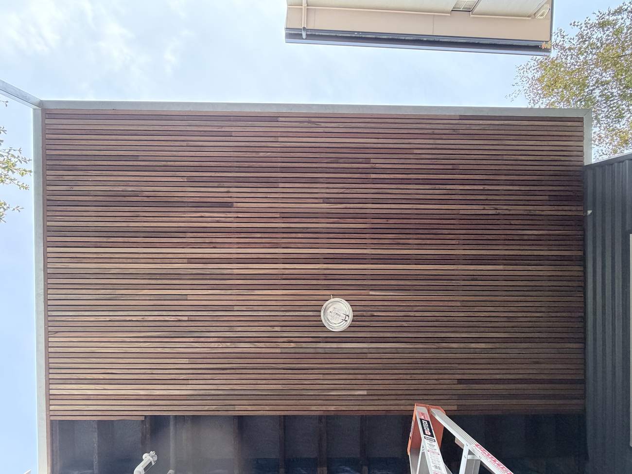 Looking up at a finished hardwood batten soffit with even gaps between every board
