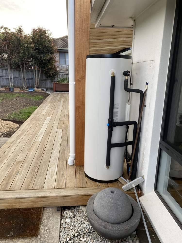 Hardwood deck and post with boards fitted tight around a hot water unit
