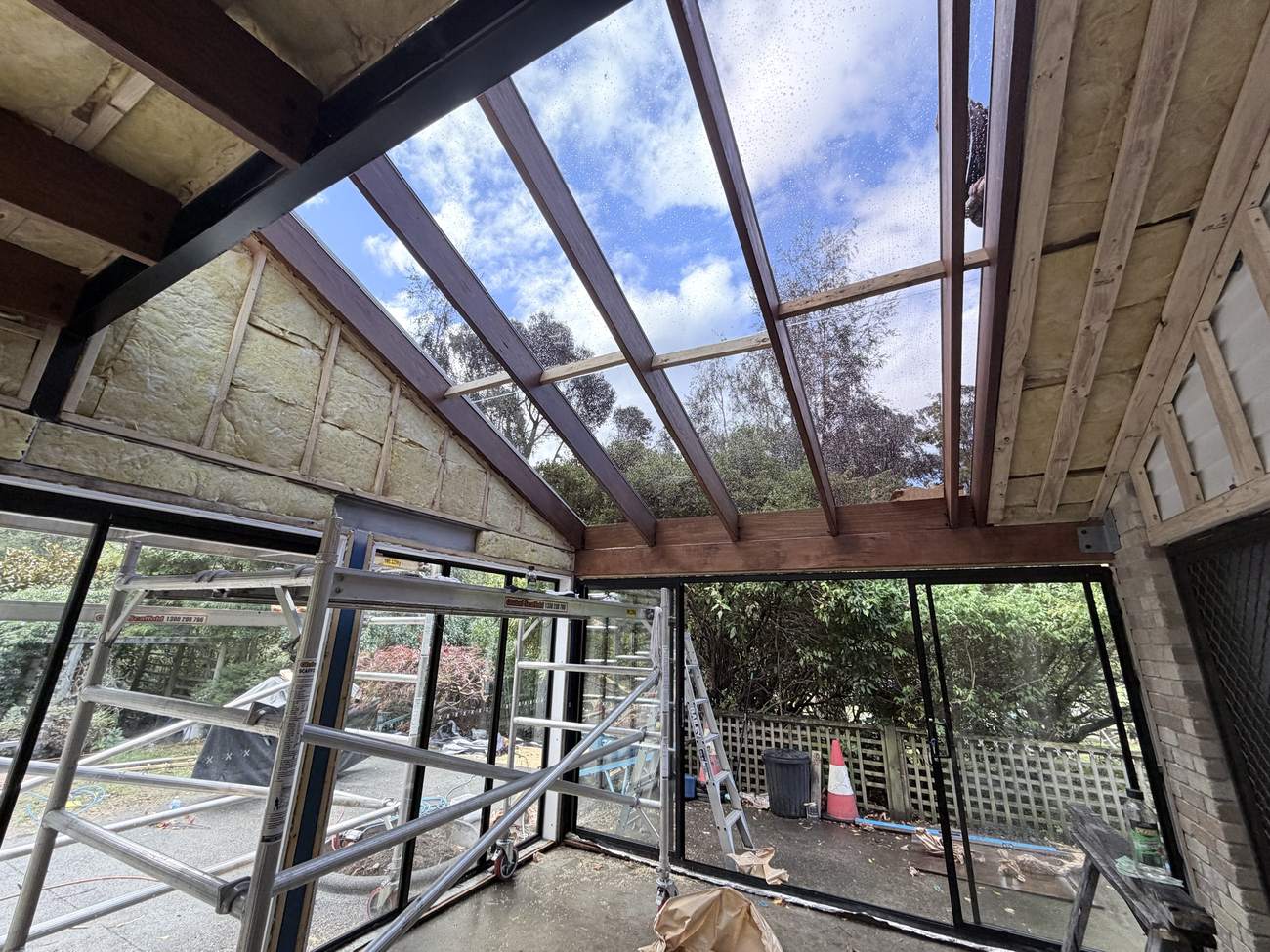 Glass roof set between hardwood rafters on a sunroom extension