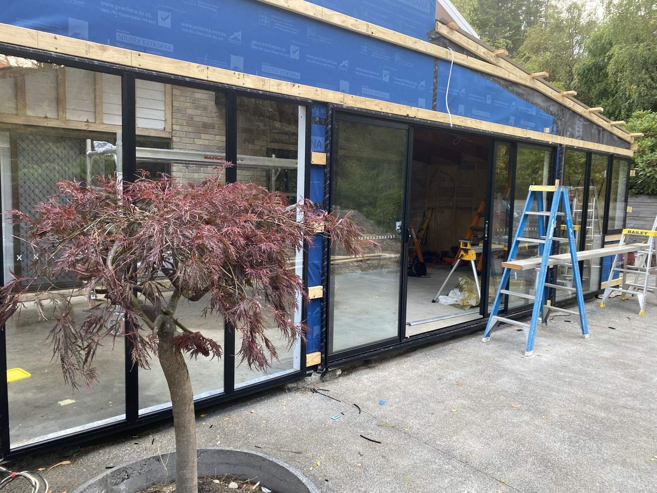 A run of new black-framed windows and a sliding door, ready for cladding
